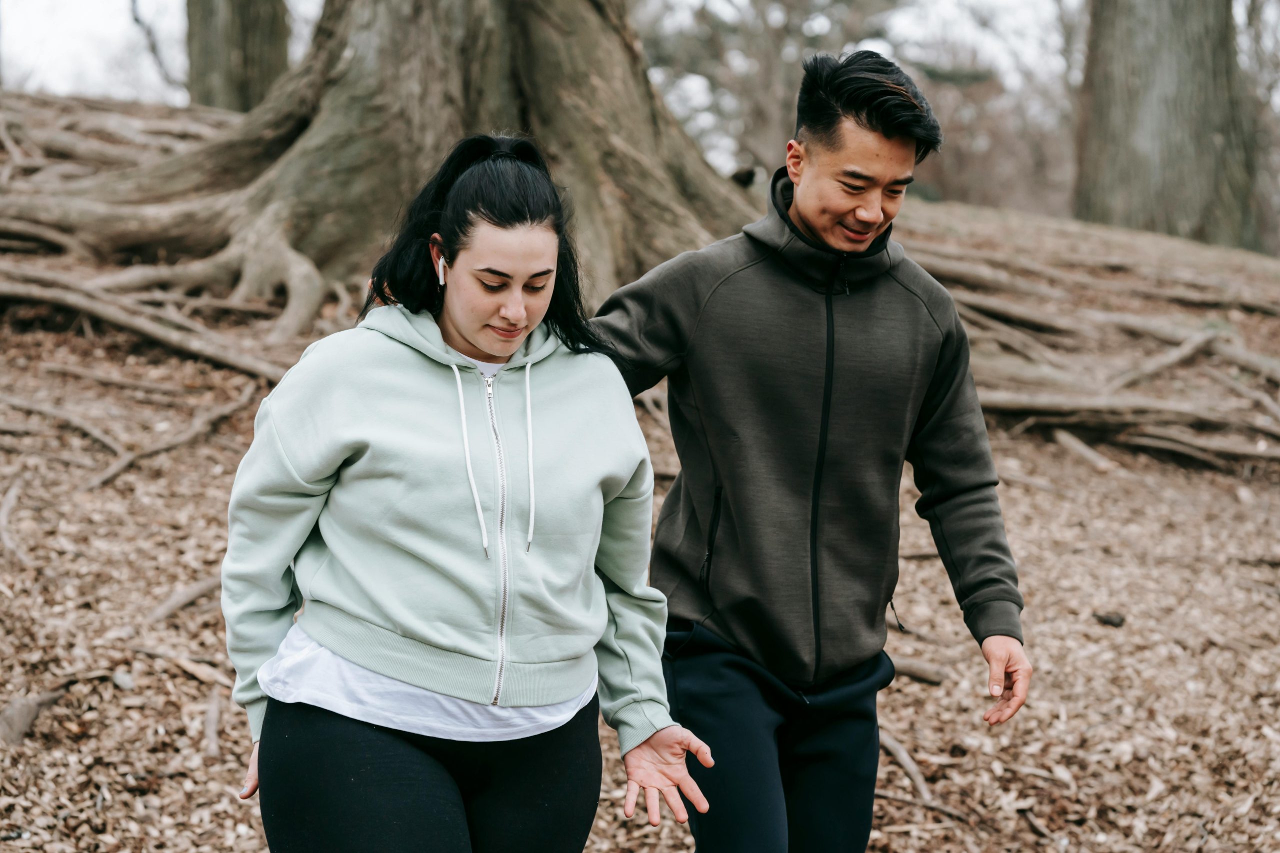 Services A personal trainer guiding a client during an outdoor exercise session in a park.