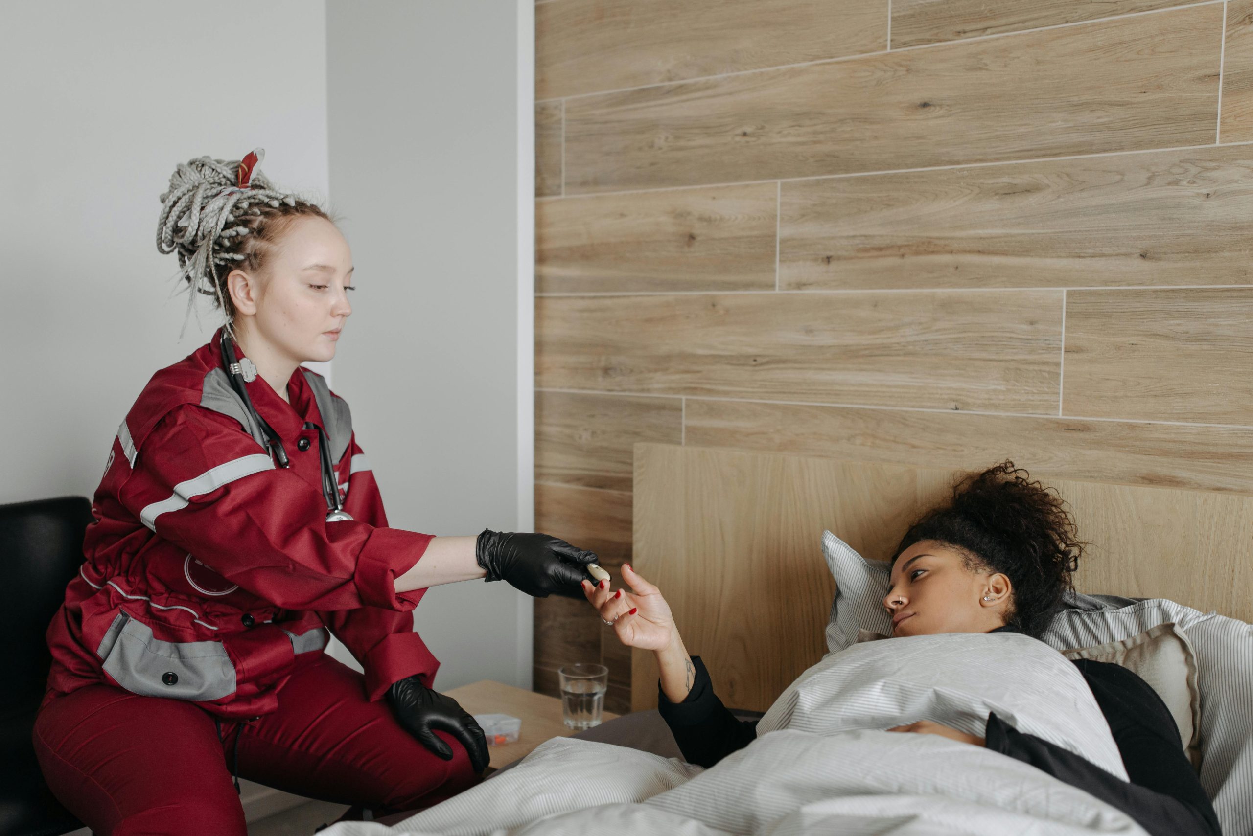 Services A paramedic provides care to a sick woman lying in bed, highlighting healthcare support at home.
